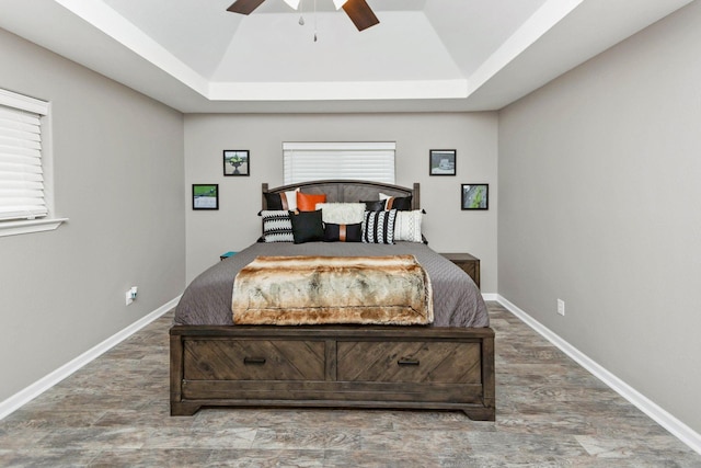 bedroom with ceiling fan, a raised ceiling, and dark hardwood / wood-style floors