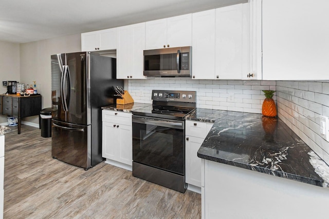 kitchen with stainless steel appliances, decorative backsplash, white cabinetry, and light hardwood / wood-style flooring