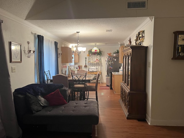 dining space featuring wood-type flooring, a textured ceiling, an inviting chandelier, and crown molding