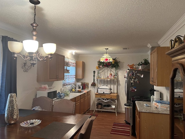 kitchen with sink, hanging light fixtures, crown molding, dark hardwood / wood-style floors, and a chandelier