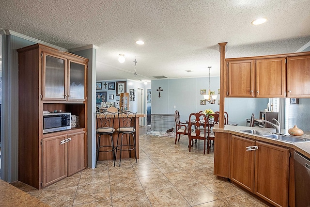 kitchen with pendant lighting, sink, ornamental molding, a textured ceiling, and stainless steel appliances