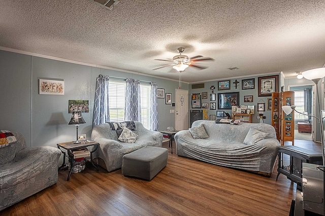 living room featuring hardwood / wood-style flooring, ceiling fan, crown molding, and a textured ceiling