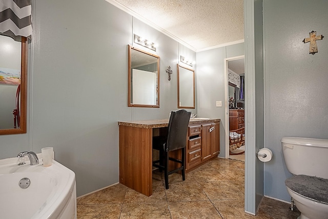 bathroom with vanity, a washtub, toilet, ornamental molding, and a textured ceiling