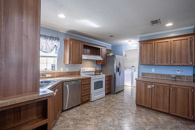 kitchen featuring ornamental molding, a textured ceiling, stainless steel appliances, washer and clothes dryer, and sink