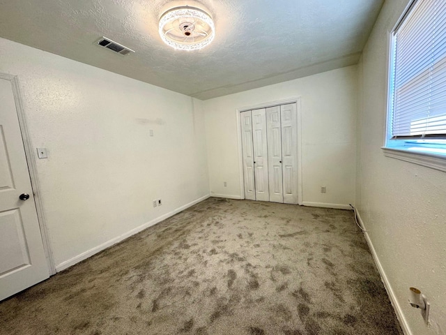 unfurnished bedroom with carpet flooring, a textured ceiling, and a closet