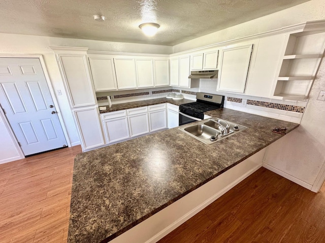 kitchen with kitchen peninsula, stainless steel gas stove, and white cabinetry