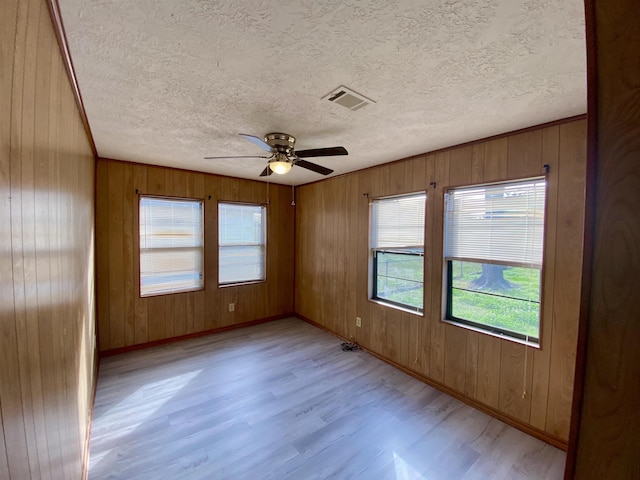 1113 Railroad, Silsbee, TX 77656 - spare room with light wood-style flooring, healthy amount of natural light, baseboards, a textured ceiling, and wooden walls
