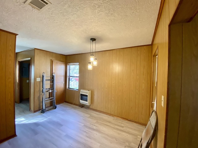 1113 Railroad, Silsbee, TX 77656 - dining space featuring heating unit, light wood-style flooring, wood walls, a textured ceiling, and baseboards