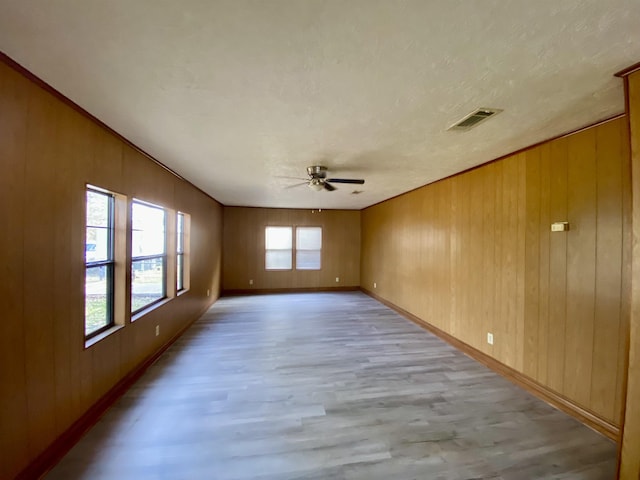 1113 Railroad, Silsbee, TX 77656 - empty room featuring light wood-style flooring, ceiling fan, and wooden walls