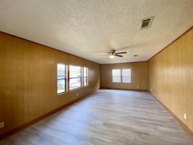 1113 Railroad, Silsbee, TX 77656 - unfurnished room featuring light wood-type flooring, a ceiling fan, a textured ceiling, and wooden walls