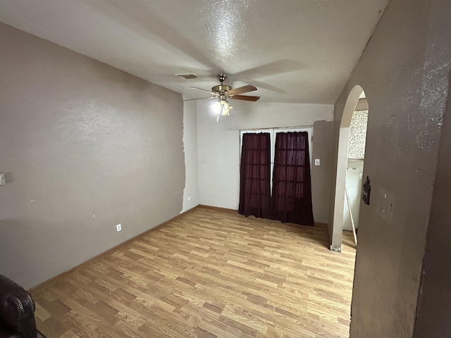 empty room featuring a textured ceiling, light wood-type flooring, and ceiling fan