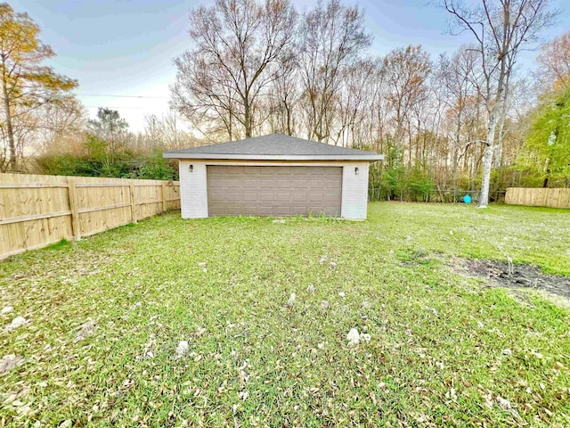 view of yard with a garage, an outbuilding, and a fenced backyard