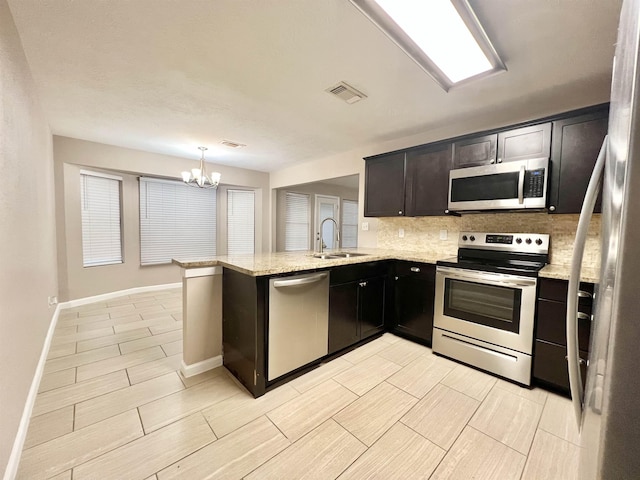 kitchen featuring visible vents, a sink, stainless steel appliances, decorative backsplash, and light stone countertops