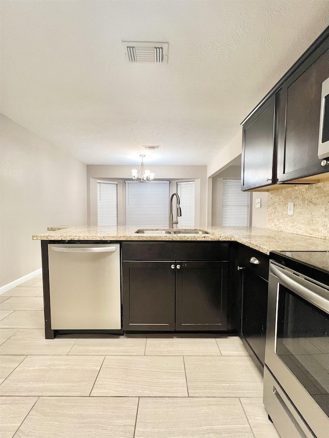 kitchen with visible vents, a sink, backsplash, stainless steel appliances, and light stone countertops