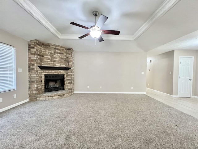 unfurnished living room with carpet flooring, a brick fireplace, a raised ceiling, and ornamental molding