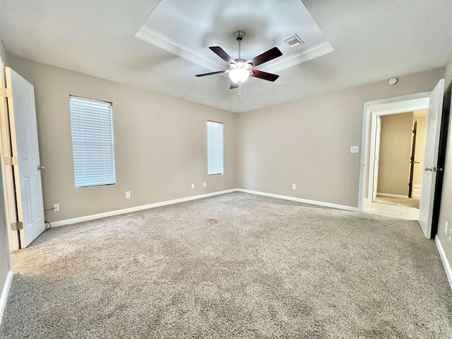 unfurnished bedroom featuring visible vents, baseboards, carpet, a raised ceiling, and a ceiling fan