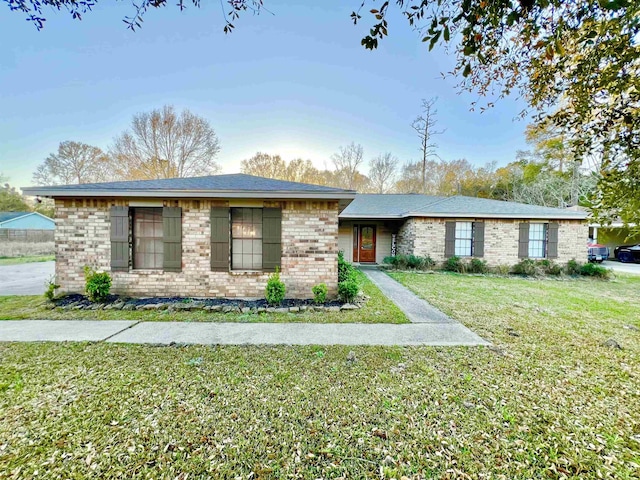 ranch-style home featuring brick siding and a front lawn