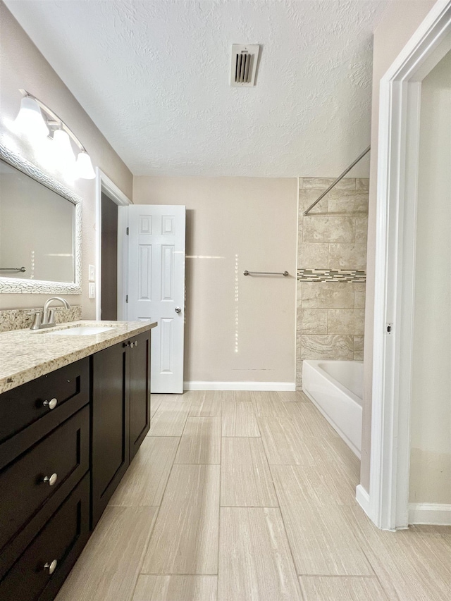 bathroom with visible vents, a textured ceiling,  shower combination, baseboards, and vanity