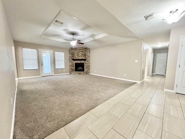 unfurnished living room with visible vents, a raised ceiling, a textured ceiling, and a brick fireplace