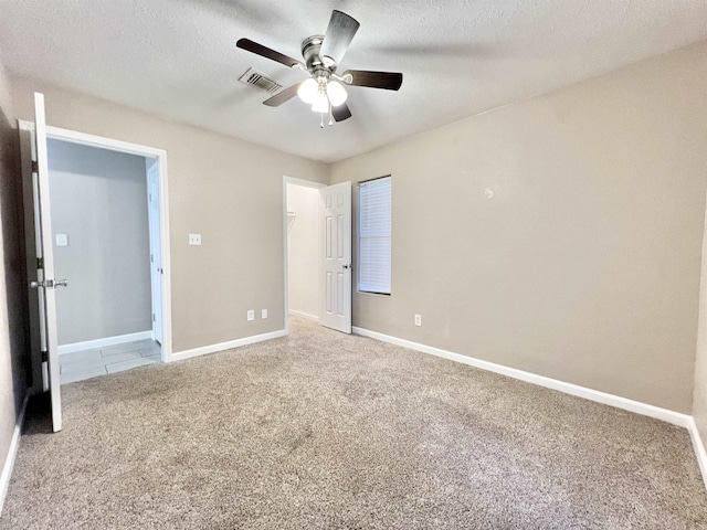 unfurnished bedroom with visible vents, carpet, baseboards, and a textured ceiling