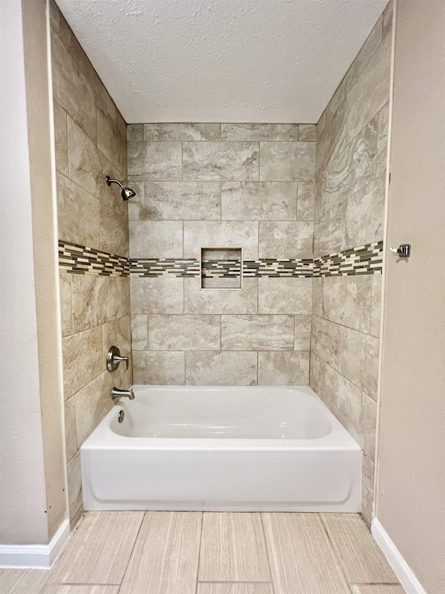 bathroom featuring a textured ceiling, shower / bath combination, and baseboards