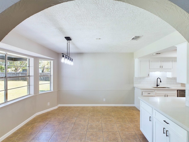 kitchen featuring backsplash, white cabinetry, sink, and decorative light fixtures