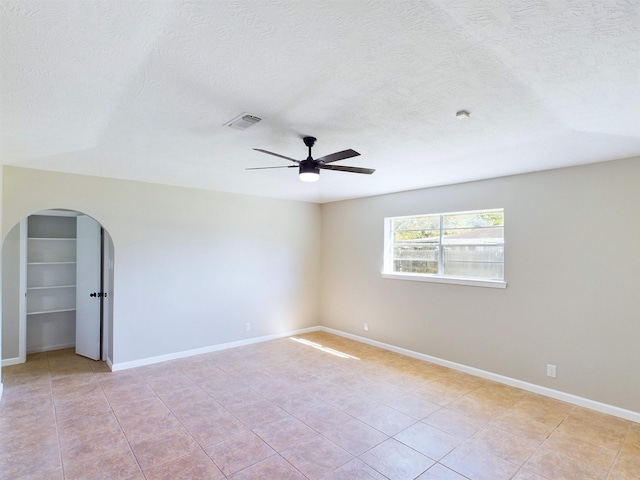 spare room with ceiling fan, light tile patterned floors, and a textured ceiling