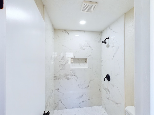 bathroom with tiled shower and toilet