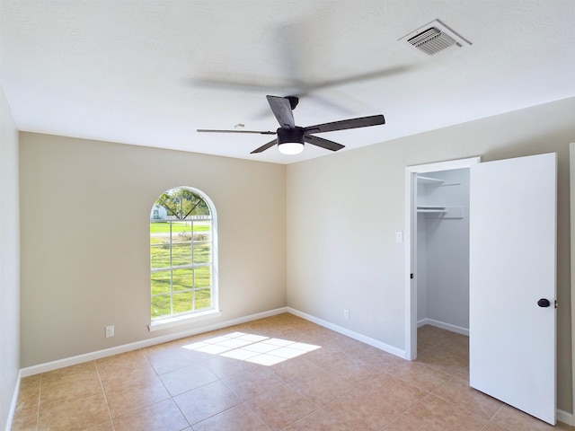 unfurnished bedroom featuring light tile patterned floors, a closet, a spacious closet, and ceiling fan