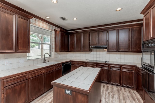 kitchen with black appliances, tile counters, light wood-type flooring, and sink