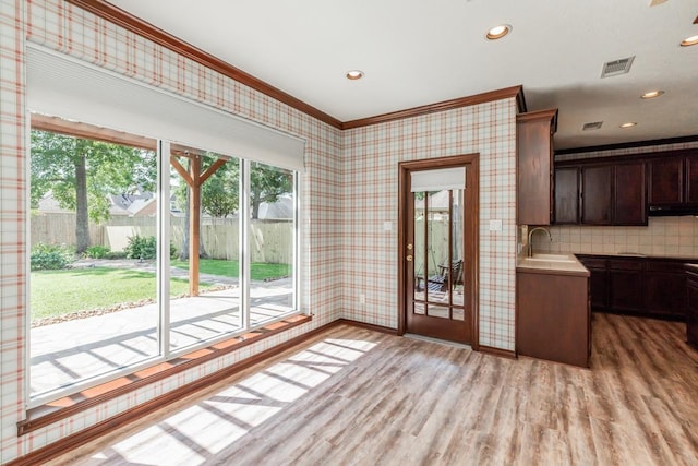 interior space featuring dark brown cabinetry, sink, tasteful backsplash, light hardwood / wood-style floors, and ornamental molding