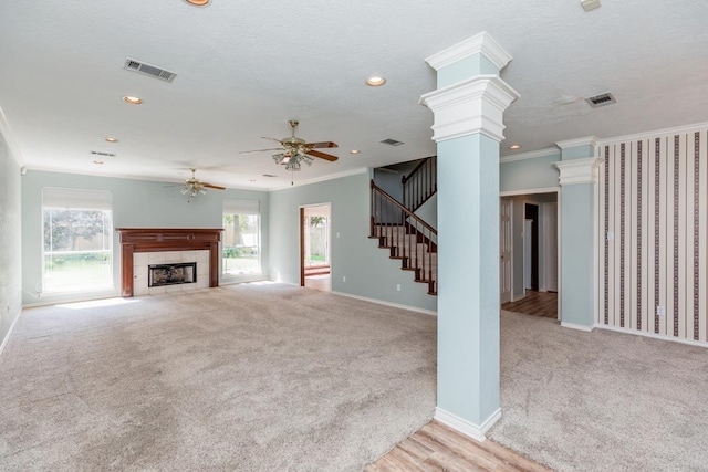 unfurnished living room with light carpet, decorative columns, ornamental molding, and a tiled fireplace