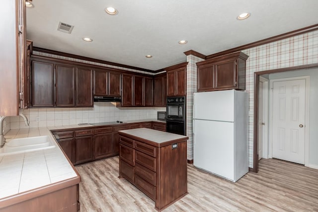 kitchen with sink, a center island, dark brown cabinets, black appliances, and ornamental molding