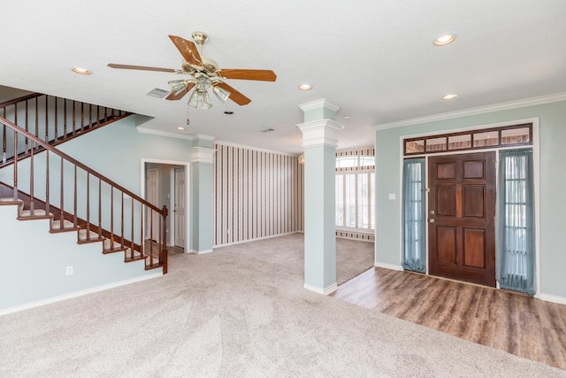 carpeted foyer entrance featuring ceiling fan, crown molding, and decorative columns