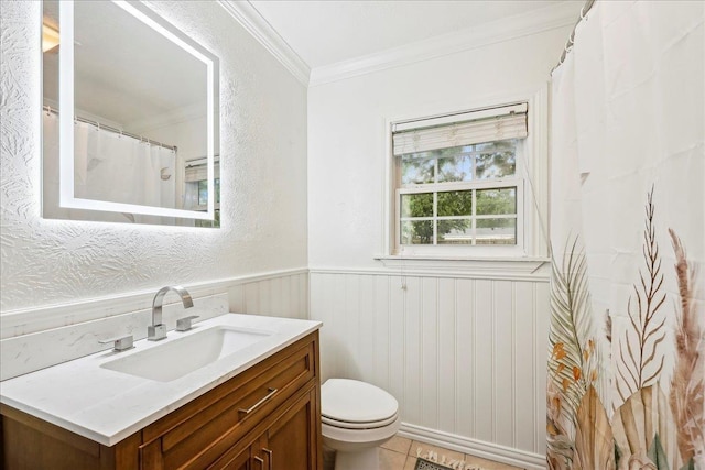 full bathroom with toilet, vanity, crown molding, tile patterned flooring, and wainscoting