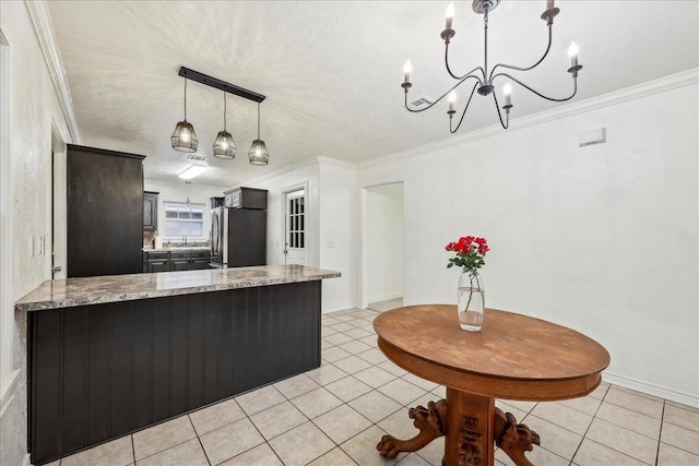 kitchen with freestanding refrigerator, a peninsula, light tile patterned floors, and ornamental molding