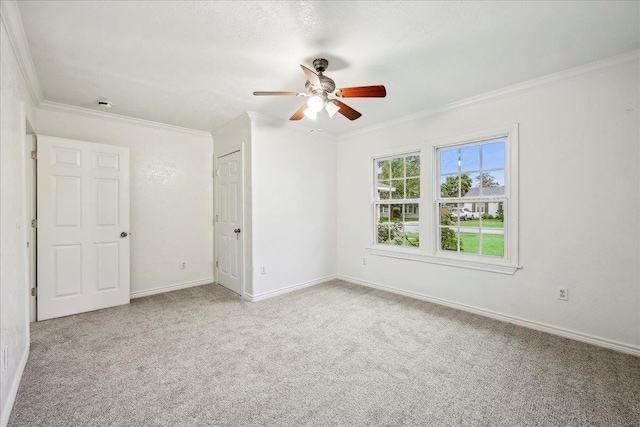 unfurnished room with crown molding, carpet floors, ceiling fan, and baseboards