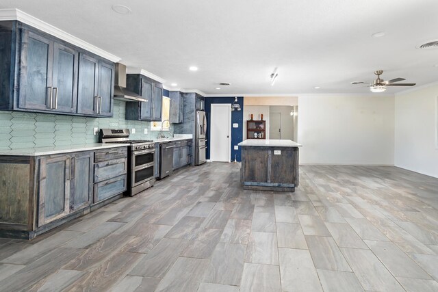 kitchen featuring tasteful backsplash, wall chimney exhaust hood, stainless steel appliances, sink, and a center island