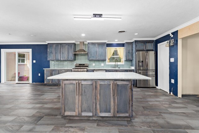 kitchen featuring sink, a kitchen island, stainless steel appliances, and wall chimney range hood