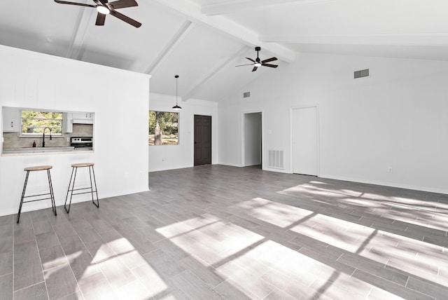 unfurnished living room featuring plenty of natural light, ceiling fan, and high vaulted ceiling