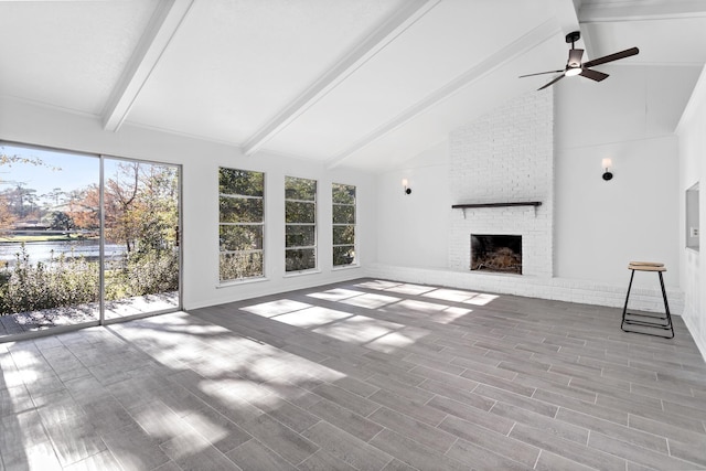 unfurnished living room featuring lofted ceiling with beams, ceiling fan, and a brick fireplace