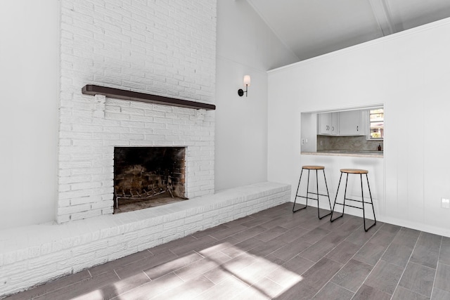 unfurnished living room featuring a fireplace and high vaulted ceiling