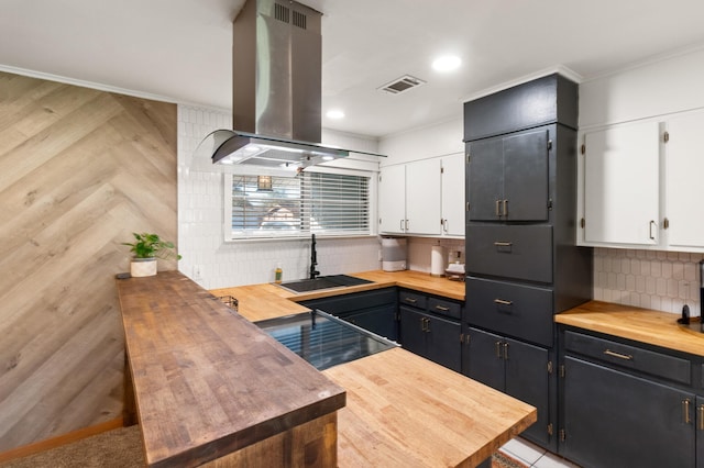 kitchen with butcher block countertops, island range hood, and white cabinets