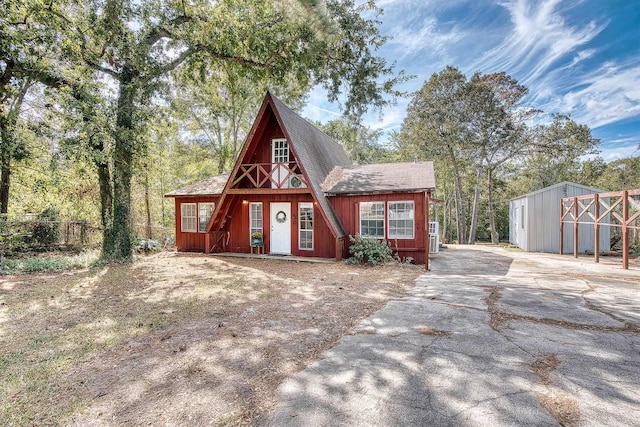 a-frame home with roof with shingles, driveway, and fence