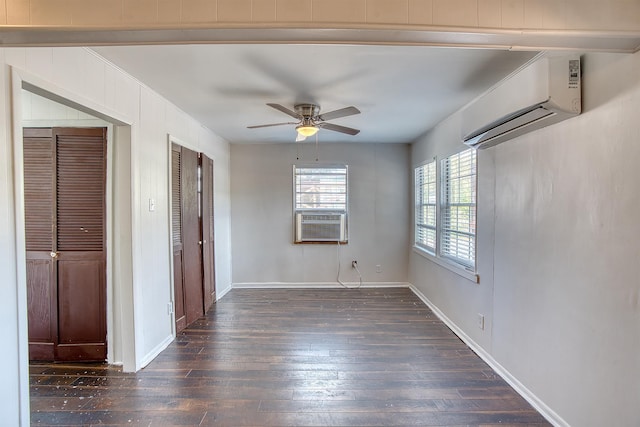 spare room featuring an AC wall unit, ceiling fan, wood-type flooring, and baseboards