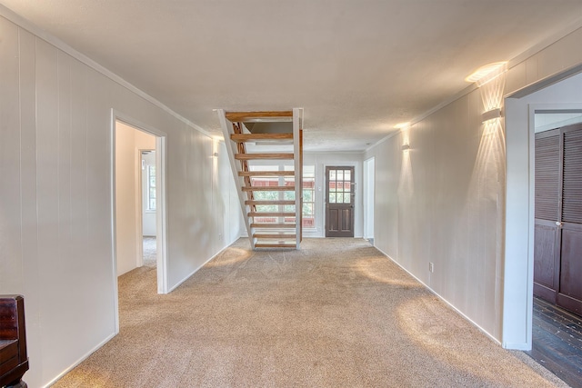 unfurnished room featuring crown molding, stairs, and carpet floors