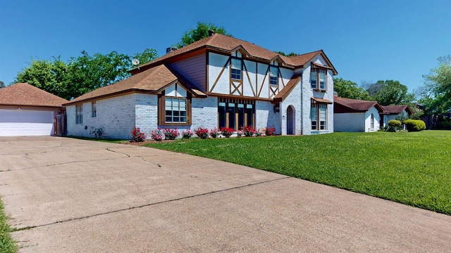 tudor house featuring brick siding, a front lawn, an outdoor structure, and a garage