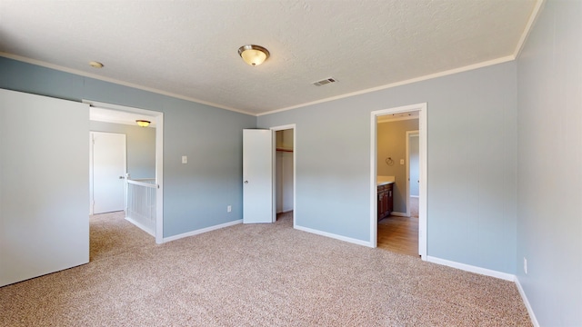 unfurnished bedroom featuring light carpet, crown molding, baseboards, a textured ceiling, and a closet