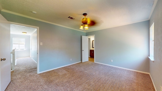 carpeted empty room featuring baseboards, a ceiling fan, ornamental molding, and a textured ceiling