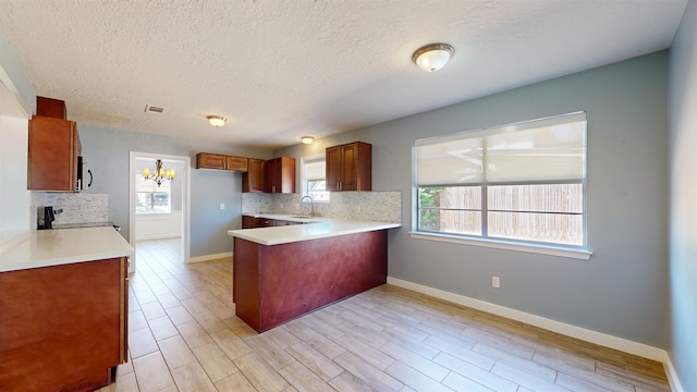 kitchen featuring a peninsula, backsplash, range, light countertops, and a textured ceiling